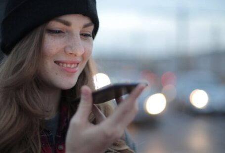Voice Search Optimization - Joyful young woman phoning on street in evening