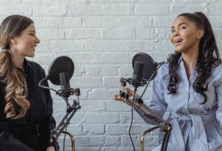 Shared And Dedicated Hosting - Smiling African American female guest gesticulating while having interview with journalist sitting near mic