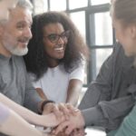 CRM Integration - Content multiethnic colleagues joining hands after coming to agreement