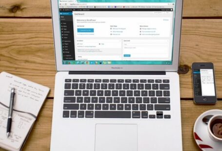 CMS - Turned-on Macbook Air Beside Black Iphone 4, Cup of Tea, and Notebook on Brown Wooden Surface