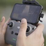 Touchscreen Compatibility - Guy flying a drone shwoing controller holding iphone dji