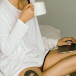 Website Content - Happy woman using laptop and drinking coffee on bed