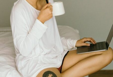 Website Content - Happy woman using laptop and drinking coffee on bed